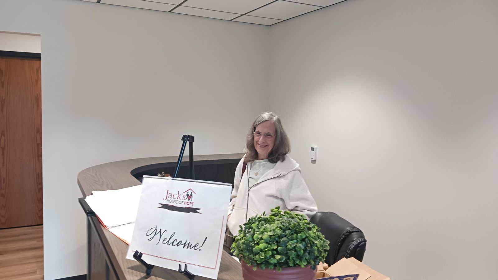A smiling woman behind a welcome counter